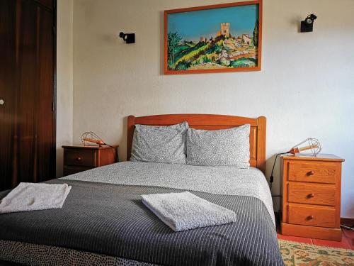 奥比多斯Óbidos - Casa do Castelo的卧室配有一张床,墙上挂有绘画作品