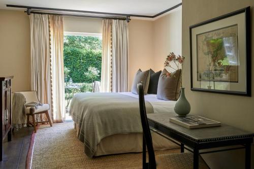 弗朗斯胡克La Clé Lodge的一间卧室配有一张床、一张桌子和一个窗户。