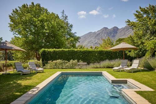 弗朗斯胡克La Clé Lodge的庭院内的游泳池,配有椅子和遮阳伞