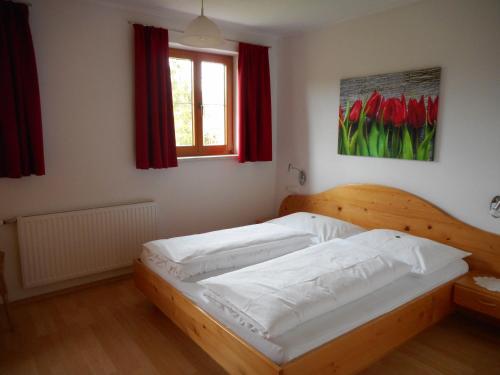 Rossleithen欣德保尔霍夫里格尔农场假期酒店的一间设有木床的卧室,位于带红色窗帘的房间