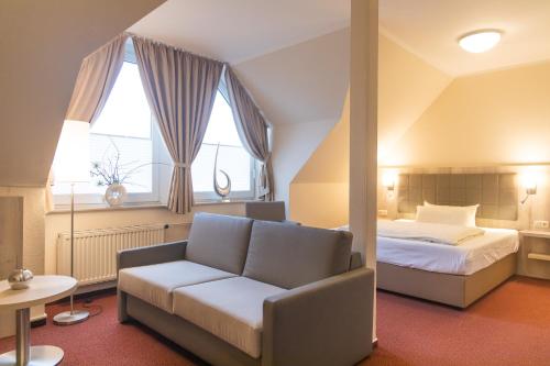 奥尔登堡奥尔登堡赫耳墨斯酒店的一间卧室配有一张床、一张沙发和窗户。
