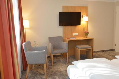 FrankenfeldLand-gut-Hotel Allerhof的酒店客房配有书桌、椅子和一张床