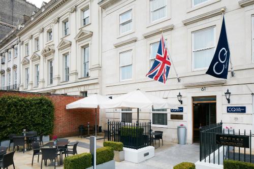 伦敦Club Quarters Hotel Covent Garden Holborn, London的大楼前有桌子和遮阳伞的酒店
