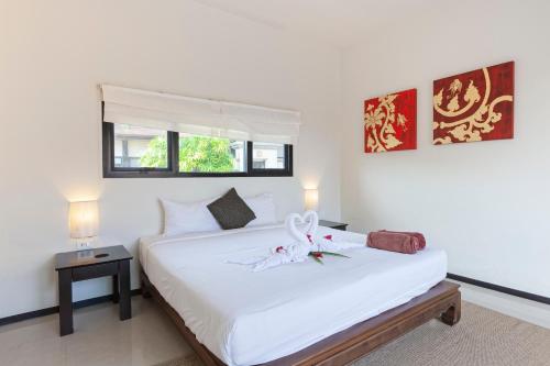 拉威海滩Foxtail Palm Villa的卧室配有白色的床,床上有花