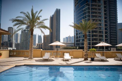 迪拜Suha JBR Hotel Apartments的一座带椅子和棕榈树的游泳池