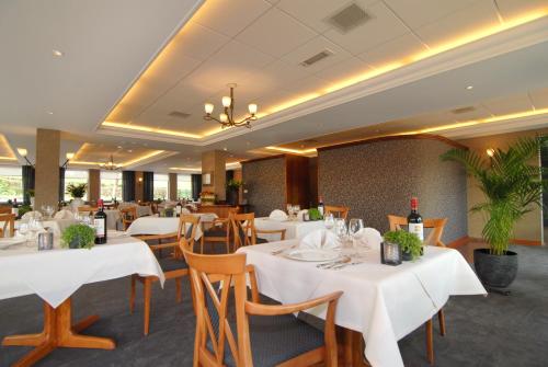 埃彭因克尔休斯酒店的用餐室配有白色的桌子和木椅