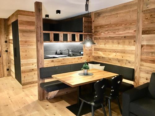 圣坎迪朵Appartements Innerkofler Mountain Home的厨房设有木墙和木桌及椅子