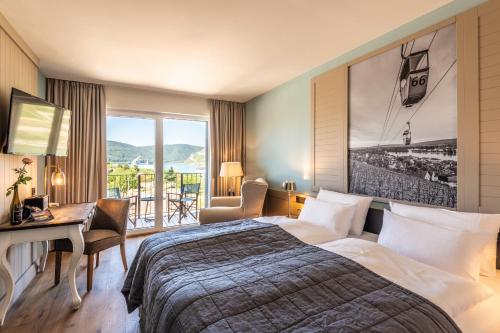 莱茵河畔的宾根PAPA RHEIN - Hotel & Spa的配有一张床、一张书桌和一扇窗户的酒店客房