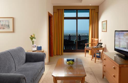 迪拜罗达海滩度假村的带沙发、桌子和电视的客厅