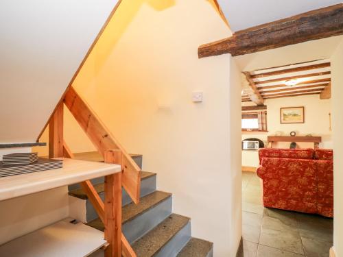 瓦斯代尔下城Stable End Cottage的楼梯通往带红色沙发的客厅