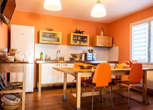 马里尼亚讷Escale villa的厨房拥有橙色的墙壁和一张木桌及椅子