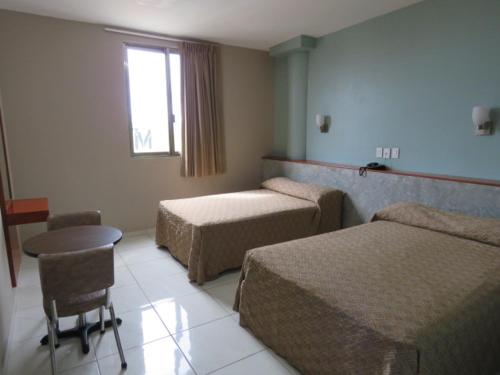 比亚埃尔莫萨Hotel San Juan Periferico的酒店客房设有两张床、一张桌子和一个窗户。