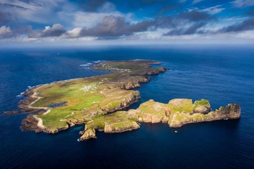 Tory IslandOstán Oileán Thoraí Tory Island Hotel的海洋中的岛屿,有绿色的岛屿