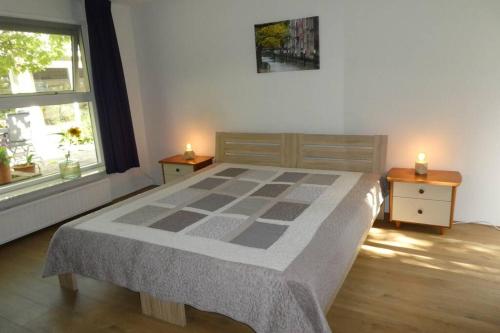 多德雷赫特Huis bij de Catalpa的一间卧室配有一张带两张桌子和两张蜡烛的床。