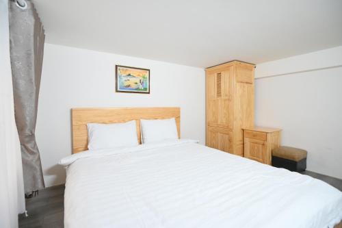 大叻Villa SEVENBAY的卧室配有白色的床和木制橱柜。