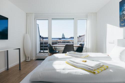 沙伊代格HEIMATEL - Ferienwohnungen的白色卧室配有两张床和一张桌子及椅子