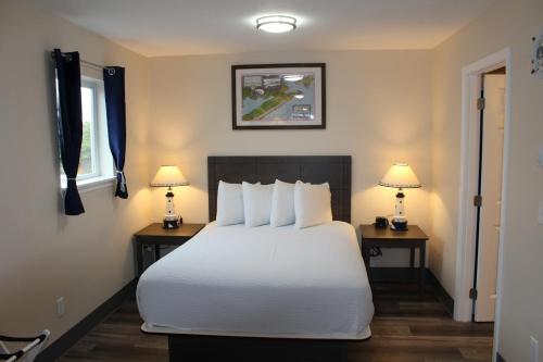 长滩Inn at the Sea的一间卧室配有一张白色的床和两张带台灯的桌子。