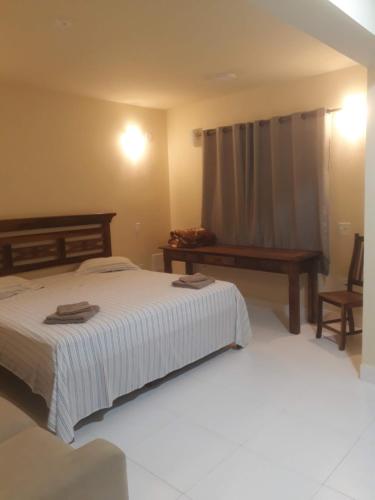 里约热内卢Fritz House的一间卧室配有一张床、一张长凳和一张桌子