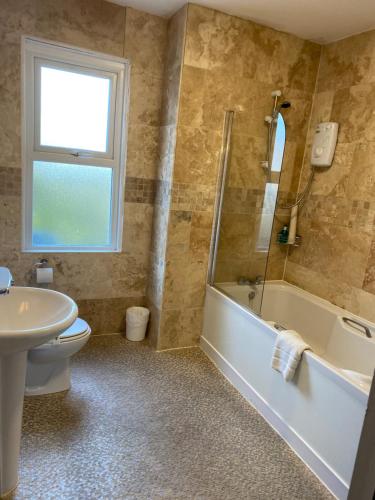 韦茅斯The Kingswood Guest House - Adult Only的带浴缸、卫生间和盥洗盆的浴室
