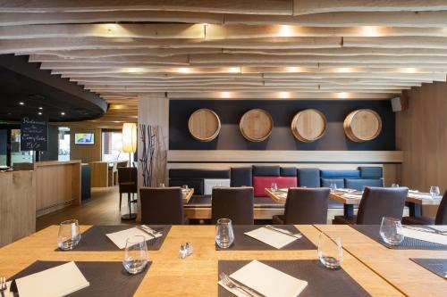 圣路易巴勒米卢斯机场宜必思酒店的墙上设有木桌和酒桶的餐厅