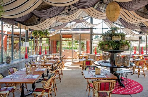 卡帕尔比奥洛坎达罗萨酒店的餐厅设有木桌、椅子和窗户。