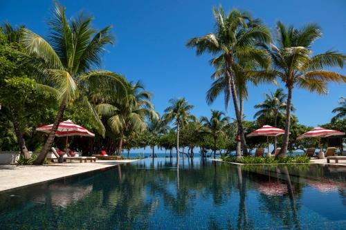 珀拉什奇亚Itz'ana Resort & Residences的度假村的游泳池拥有棕榈树和遮阳伞