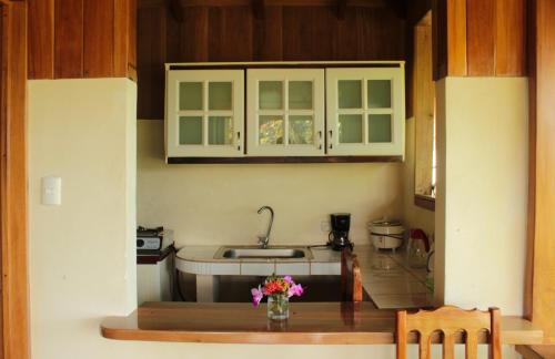 德雷克Casa Horizontes Corcovado的厨房配有白色橱柜和鲜花桌