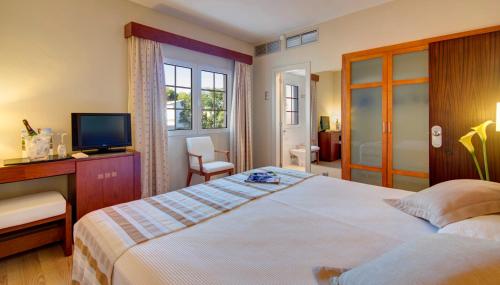 休达德亚Hotel Patricia Menorca的一间卧室配有一张大床和电视