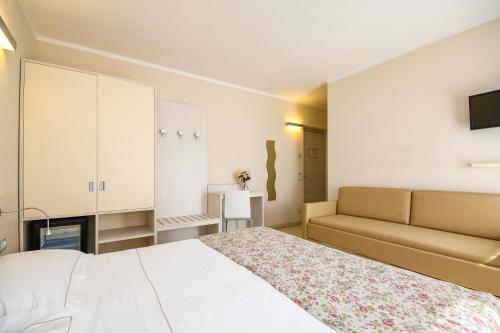 拉齐塞Locanda Corte Montioni的卧室配有白色的床和沙发