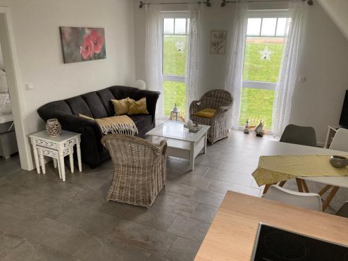 OldenswortFerienhaus-Hemmerdeich的客厅配有沙发、椅子和桌子