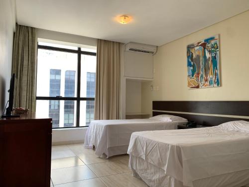 萨尔瓦多Flat Athenas 1402的酒店客房设有两张床和窗户。