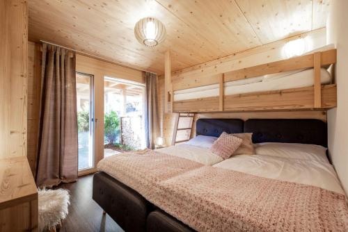 格林德尔瓦尔德Chalet CARVE - Apartments EIGER, MOENCH and JUNGFRAU的木制客房内的一间卧室,配有一张床