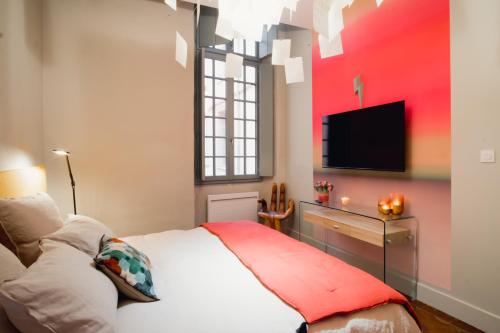 蒙托邦room five - parking, balnéothérapie, place nationale, un havre de paix的一间卧室配有一张床,墙上配有电视