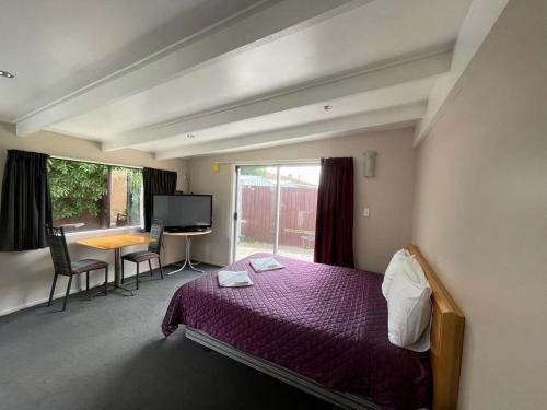 基督城布伦海姆路汽车旅馆的一间卧室配有一张床、一张书桌和一个窗户。