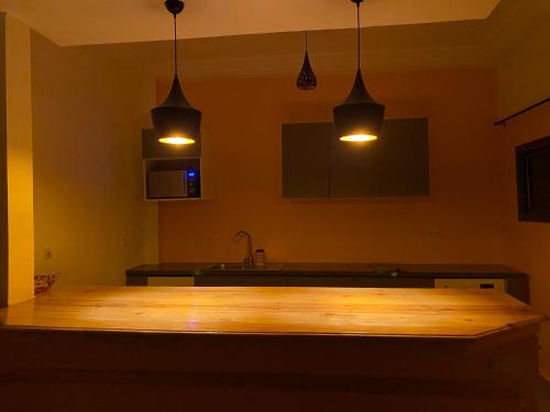 圣路易斯Gîte Le Toubé的厨房配有2盏吊灯和一张木桌