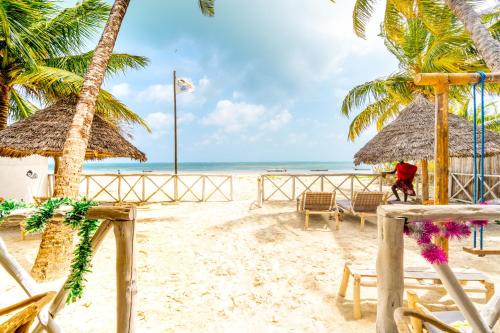 布韦朱The African Paradise Beach Hotel的海滩上,有椅子和棕榈树,还有大海