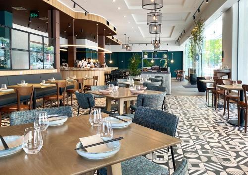 奥克兰Sudima Auckland City的一间带木桌椅的餐厅和一间酒吧