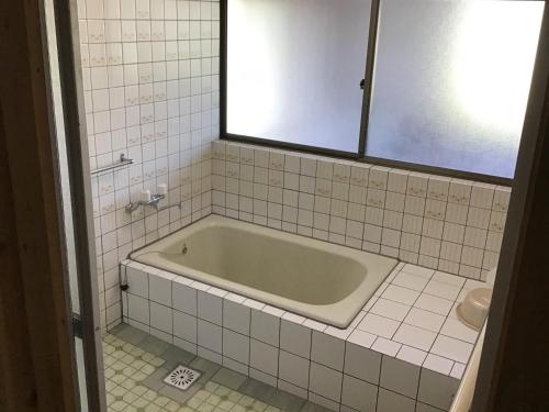 真庭市富乃亭的白色瓷砖浴室内的浴缸