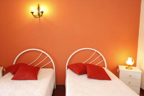 CapeloCasa capelinhos的客房内的两张床和红色枕头