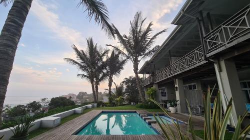 巴利托Shaka's Seat Guesthouse - Check Out Our May Special!的棕榈树屋前的游泳池