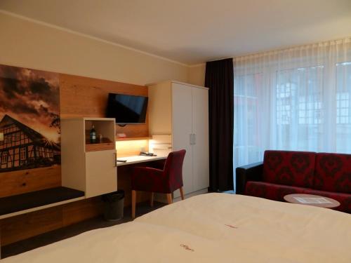巴特埃森胡歌餐厅酒店的酒店客房配有一张床、一张书桌和一张沙发。