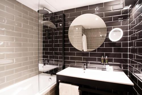 费内-伏尔泰Appart'City Collection Genève Aéroport - Ferney Voltaire的黑色瓷砖浴室设有水槽和镜子