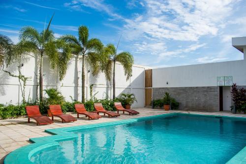 马那瓜Hotel Agualcas的一座带椅子和棕榈树的游泳池,毗邻一座建筑