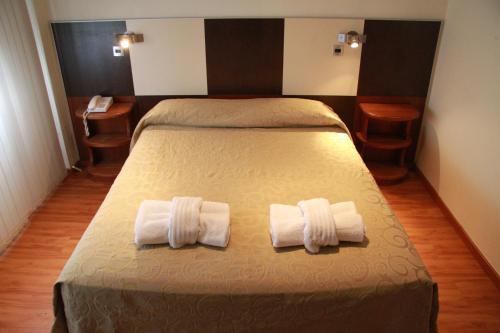 圣拉斐尔卡尔顿酒店的一间卧室配有一张床,上面有两条毛巾