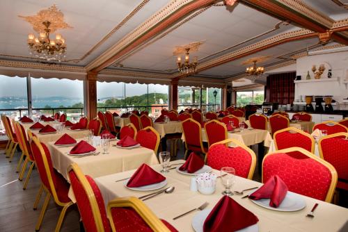 伊斯坦布尔金角湾酒店的用餐室配有桌椅和红色座椅