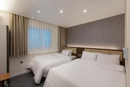 釜山Busan Lounge 26 Hotel的酒店客房设有两张床和窗户。