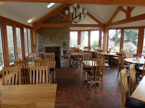 PuncknowleThe Manor House的餐厅设有木桌、椅子和壁炉