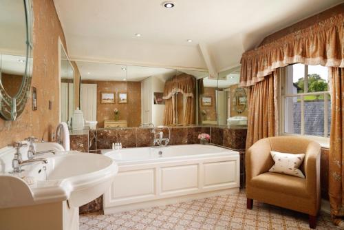 厄维召特Summer Lodge Country House Hotel的带浴缸、椅子和水槽的浴室