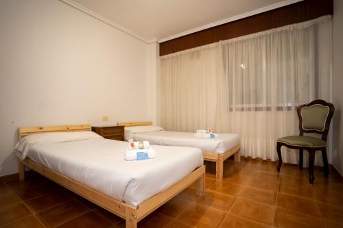 费罗尔TuristiQA - Piso Carballo Ferrol VUTCO01445的酒店客房,配有两张床和椅子