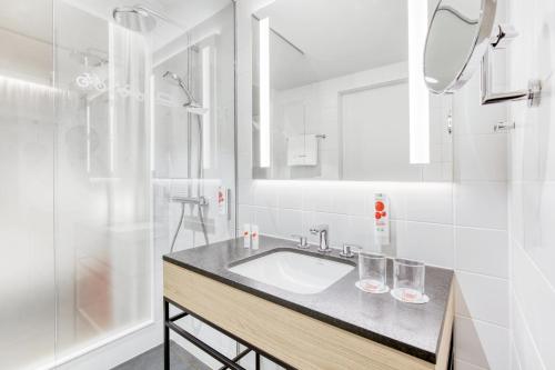 威斯巴登IntercityHotel Wiesbaden的白色的浴室设有水槽和淋浴。